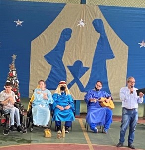 Grupo de alunos, professores e funcionários da Escola Metodista O Semeador, além de um cachorro, usando trajes temáticos da Celebração de Natal.