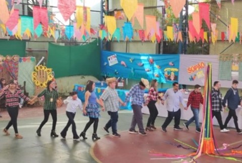 Grupo de alunos, professores e funcionários da Escola Metodista O Semeador, além de um cachorro, usando trajes temáticos da Celebração de Natal.