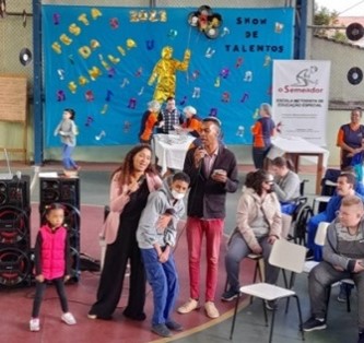 Grupo de alunos, professores e funcionários da Escola Metodista O Semeador, além de um cachorro, usando trajes temáticos da Celebração de Natal.